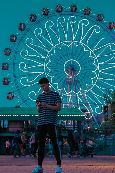 In the evening, a woman dressed in red and white striped shirt standing near the ferris wheel
